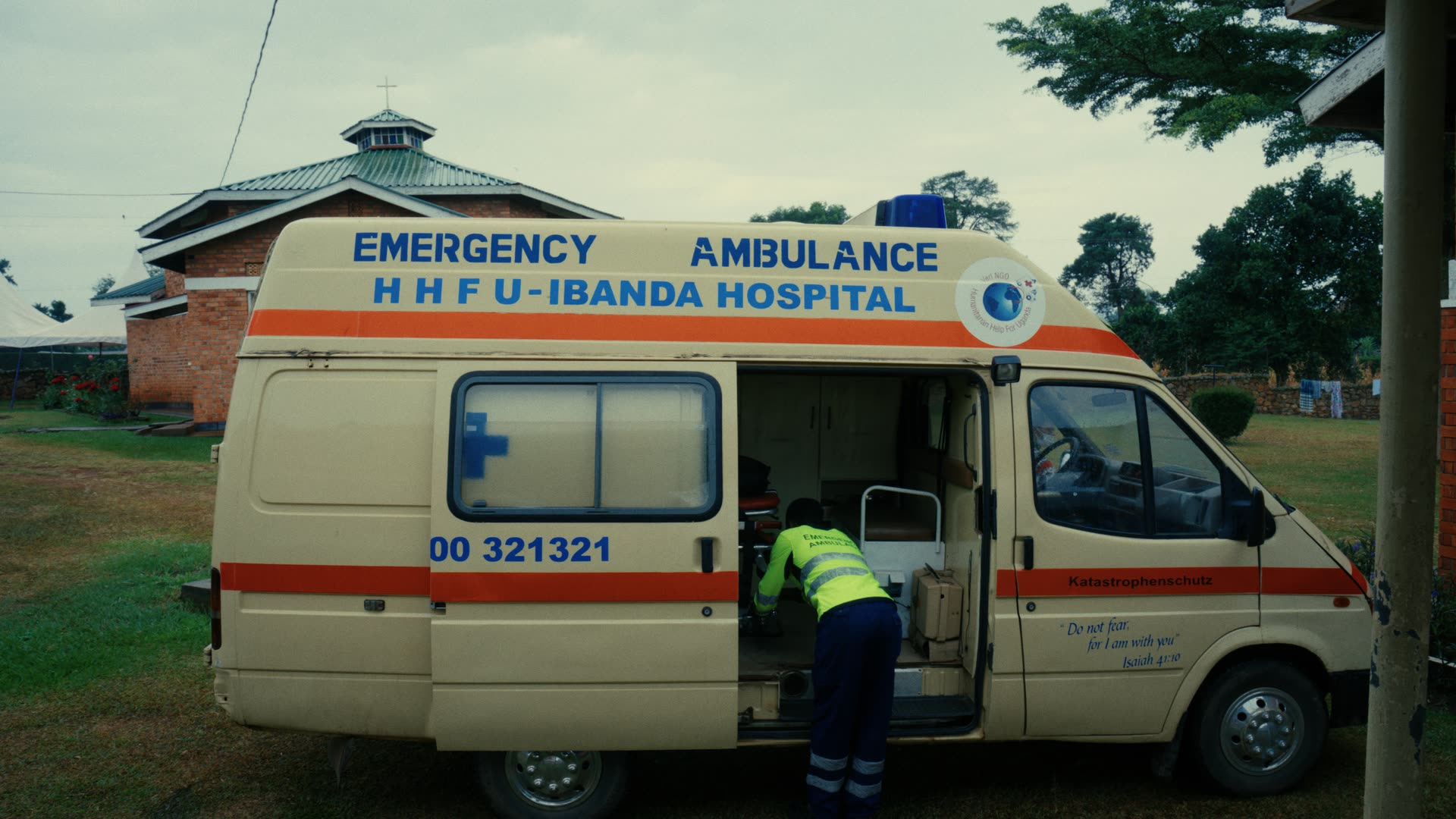 Krankenwagen mit der Aufschrift „Emergency Ambulance HHFU – Ibanda Hospital“; ein Sanitäter steigt hinten ein.